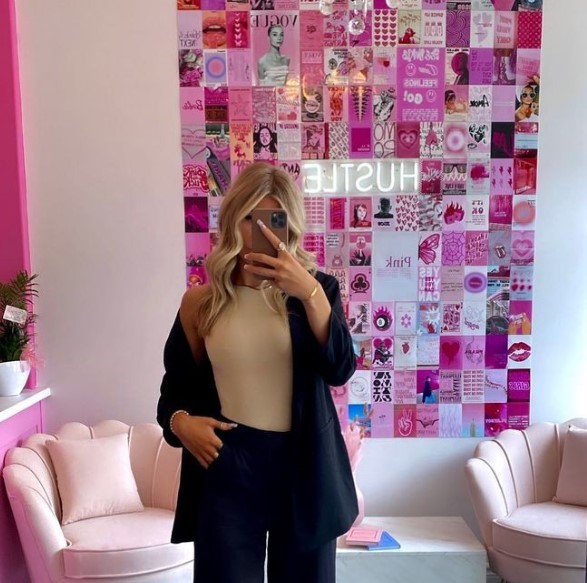 woman in front of pink collage with neon hustle in the background