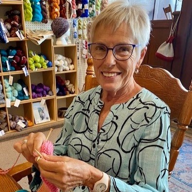 Joan Spence knitting at wooden table