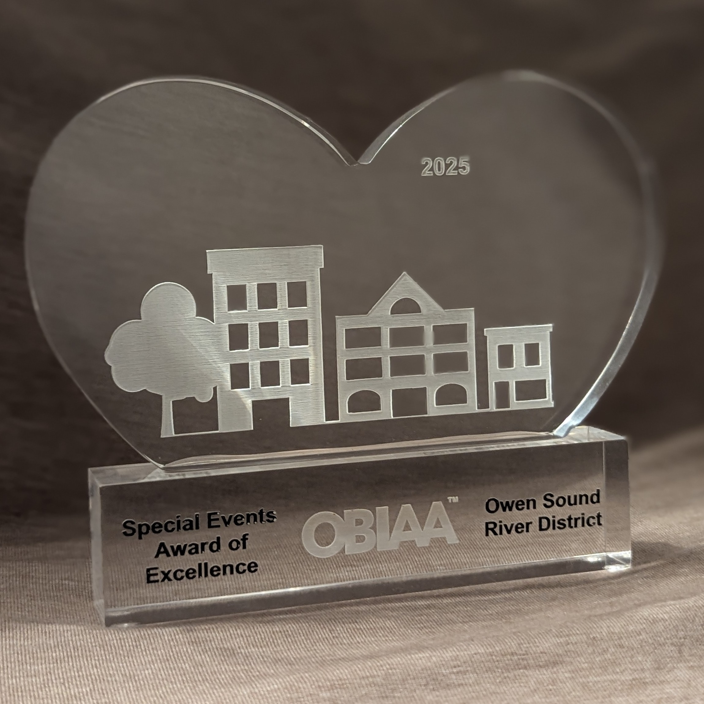 photo of clear heart shaped trophy with city scape including black text on the base