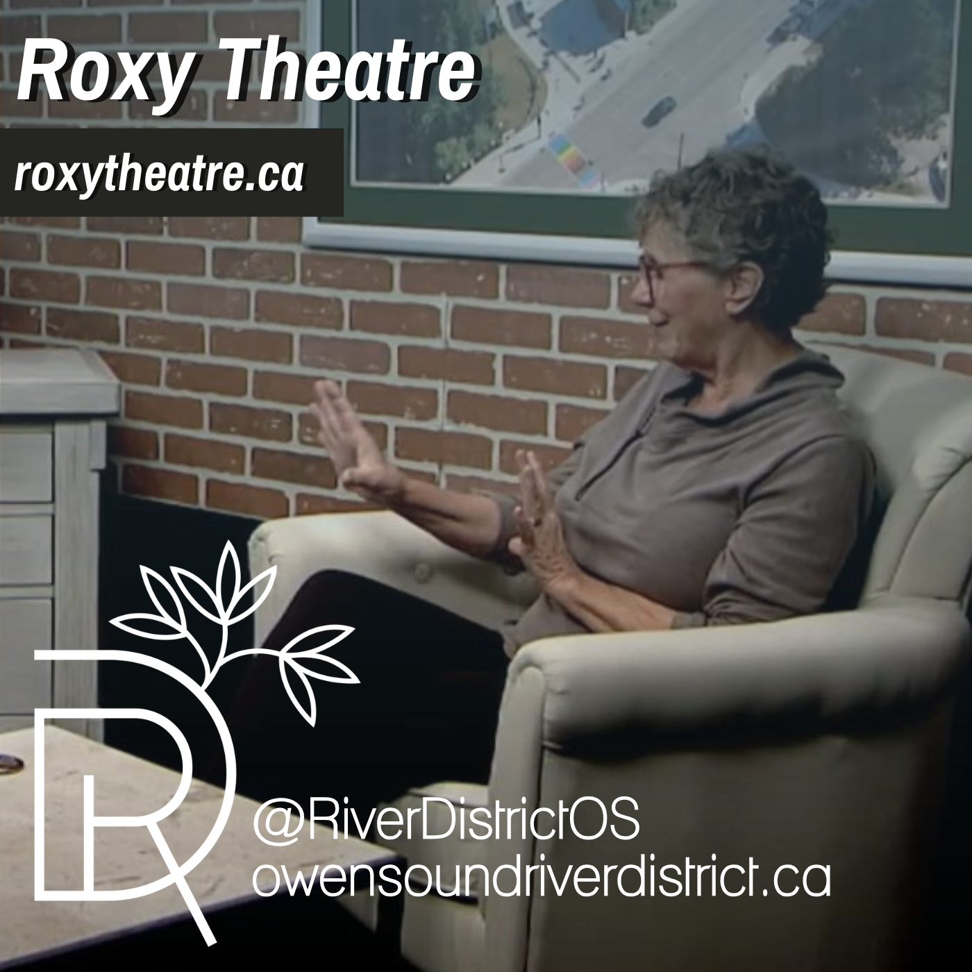Cory lapoint sitting in a white club chair against a faux brick wall and large painting